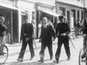 Two policemen escort Hans Vollenweider to his trial.