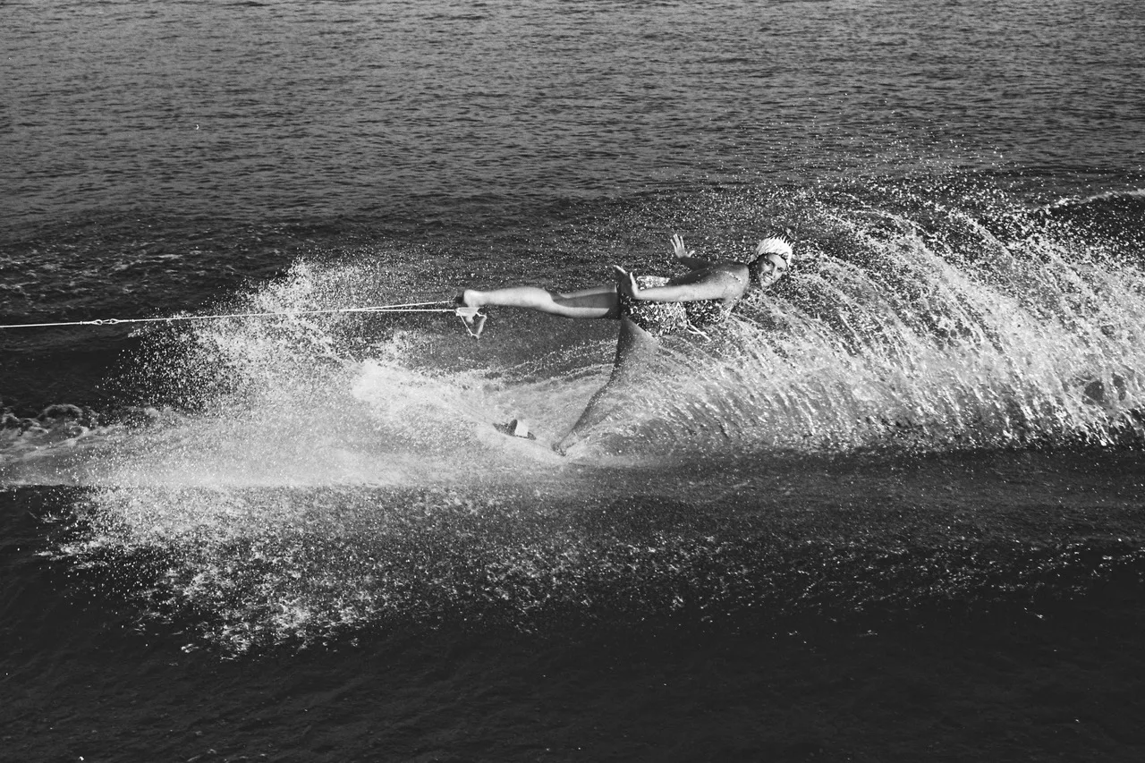 Alice Baumann zeigt den «Backward swan», eine Figur, bei das Seil am Fuss eingehängt wird und die Wasserskifahrerin rückwärts auf einem Bein gezogen wird, 1962.