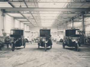 Blick in die Fabrikhalle der Firma Tribelhorn AG in Altstetten mit aufgereihten elektrischen Post-Dreirädern, um 1920.