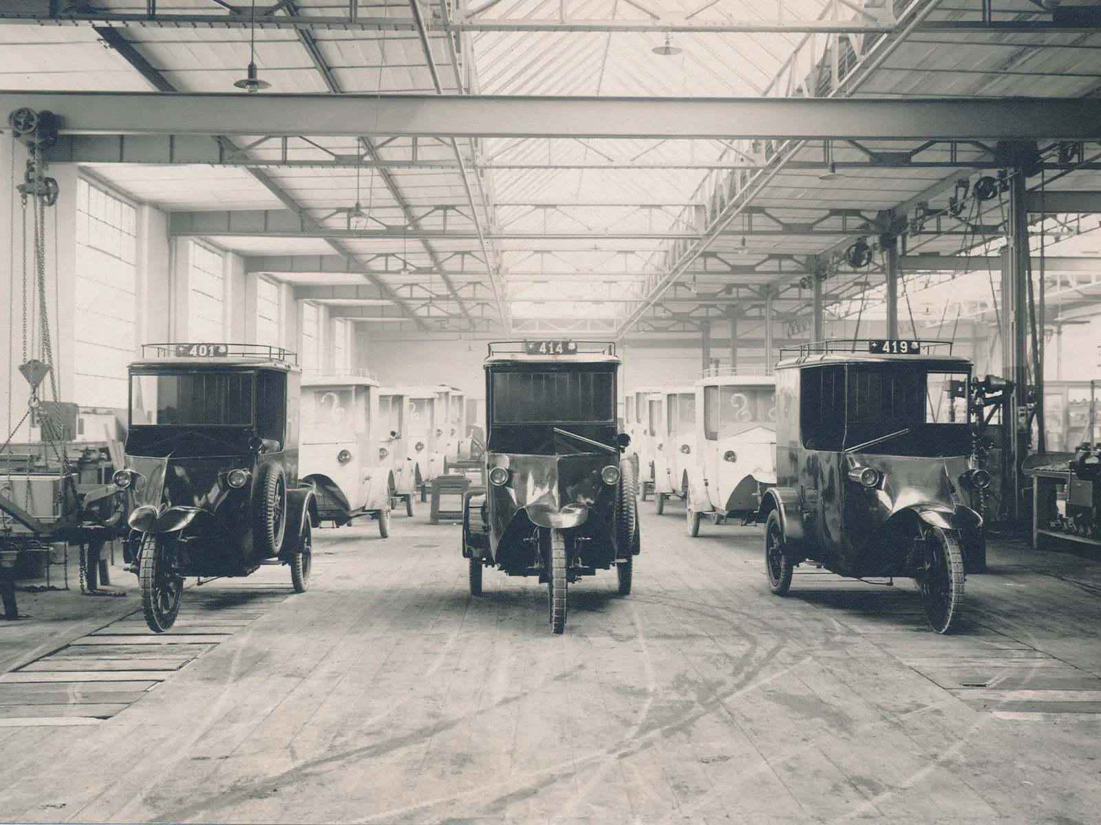 Blick in die Fabrikhalle der Firma Tribelhorn AG in Altstetten mit aufgereihten elektrischen Post-Dreirädern, um 1920.