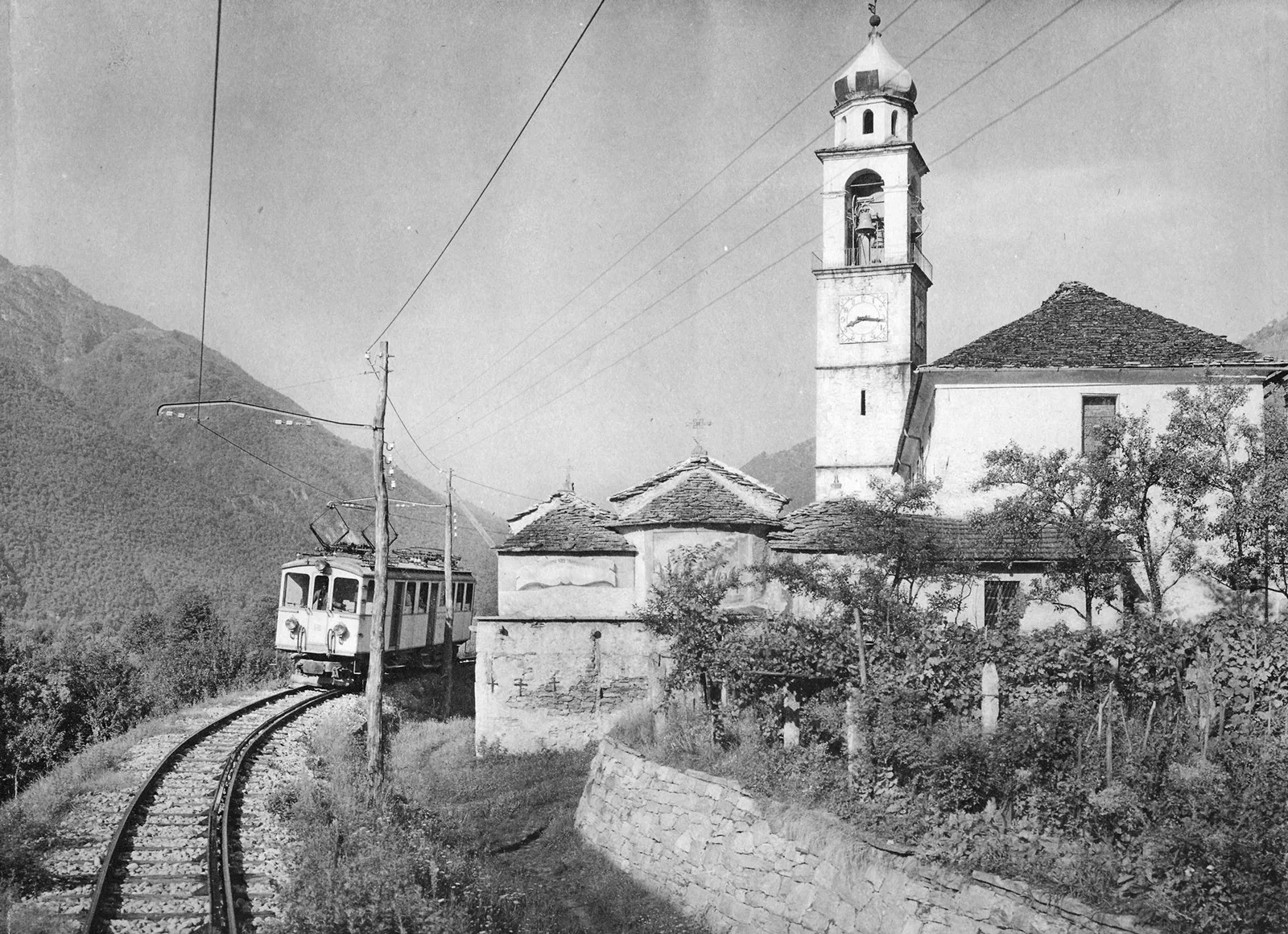 Der Elektrotriebwagen BCFe 4/4, Nr. 18, der Centovalli-Bahn passiert am 24.8.1925 die Pfarrkirche von Tegna.