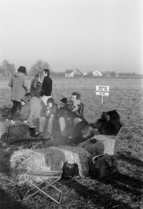 Protestors sitting on bales of hay and keeping warm by the fire.