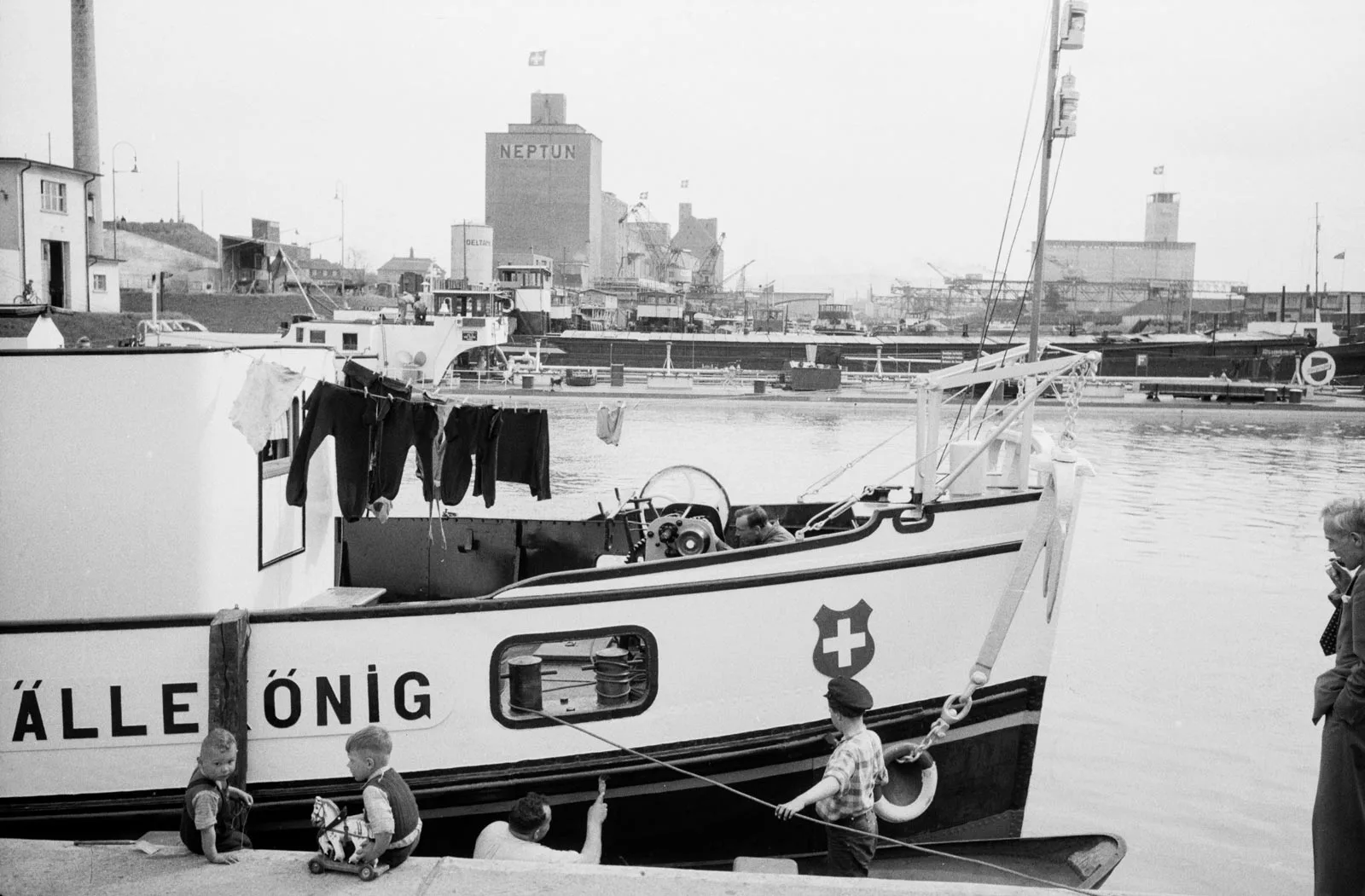 Enfants jouant devant le bateau à moteur «Lällekönig» dans le port de Bâle-Petit-Huningue, 1955.