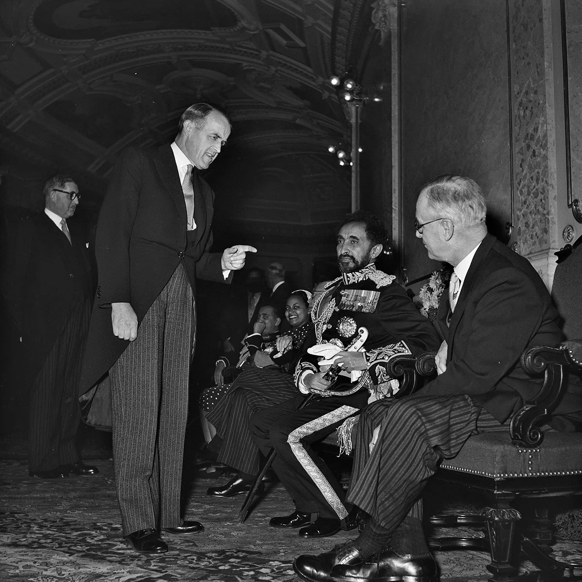 Haile Selassie I. in der Wandelhalle des Bundehauses im Gespräch mit Bundesrat Max Petitpierre (links) und Bundespräsident Rodolphe Rubattel (rechts).