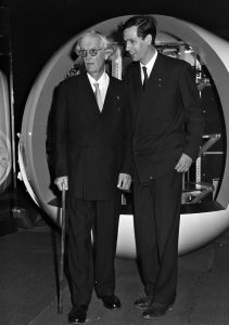 Auguste (left) and Jacques Piccard pose in front of a model of the bathyscaphe diving sphere, May 1960.