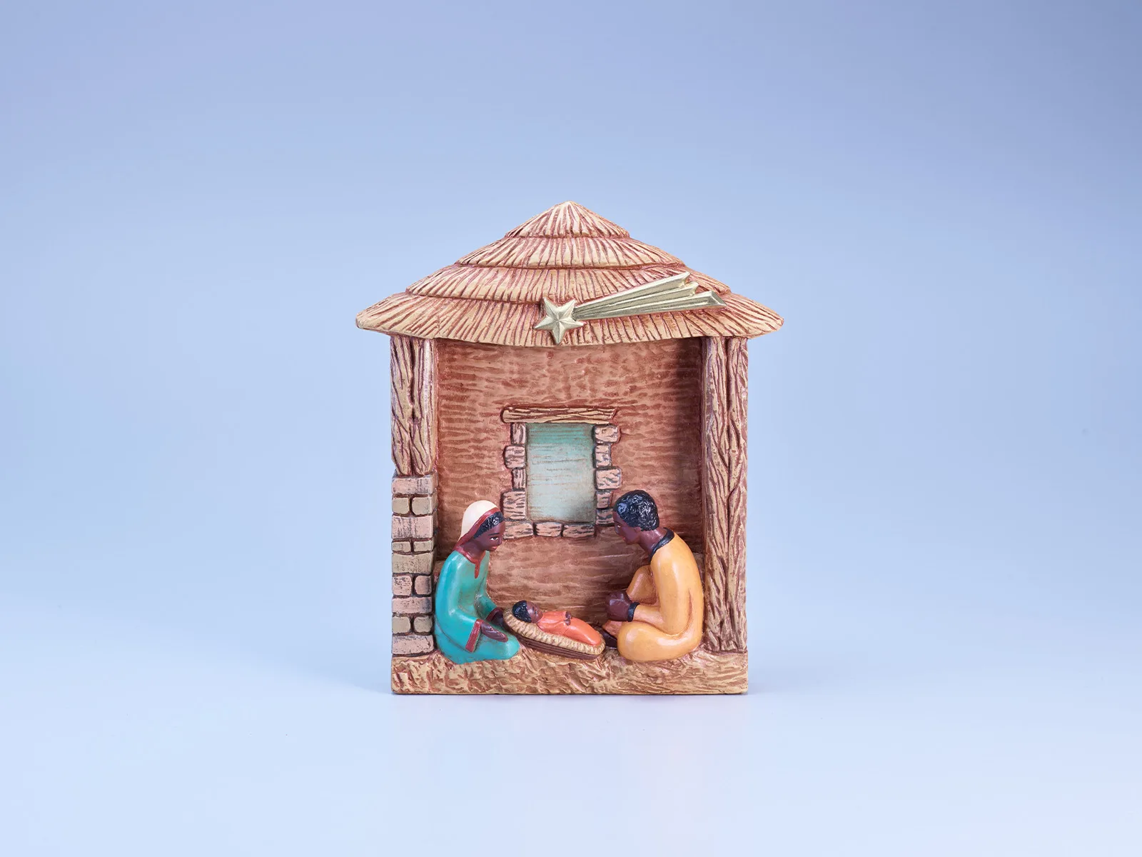 Diese Tonkrippe aus dem Senegal stellt die Geburtsszene in einem einfachen Unterstand dar, der mit Schilf eingedeckt ist. Entsprechend dem Herkunftsland ist die Heilige Familie von schwarzer Hautfarbe und trägt traditionelle Kleidung.