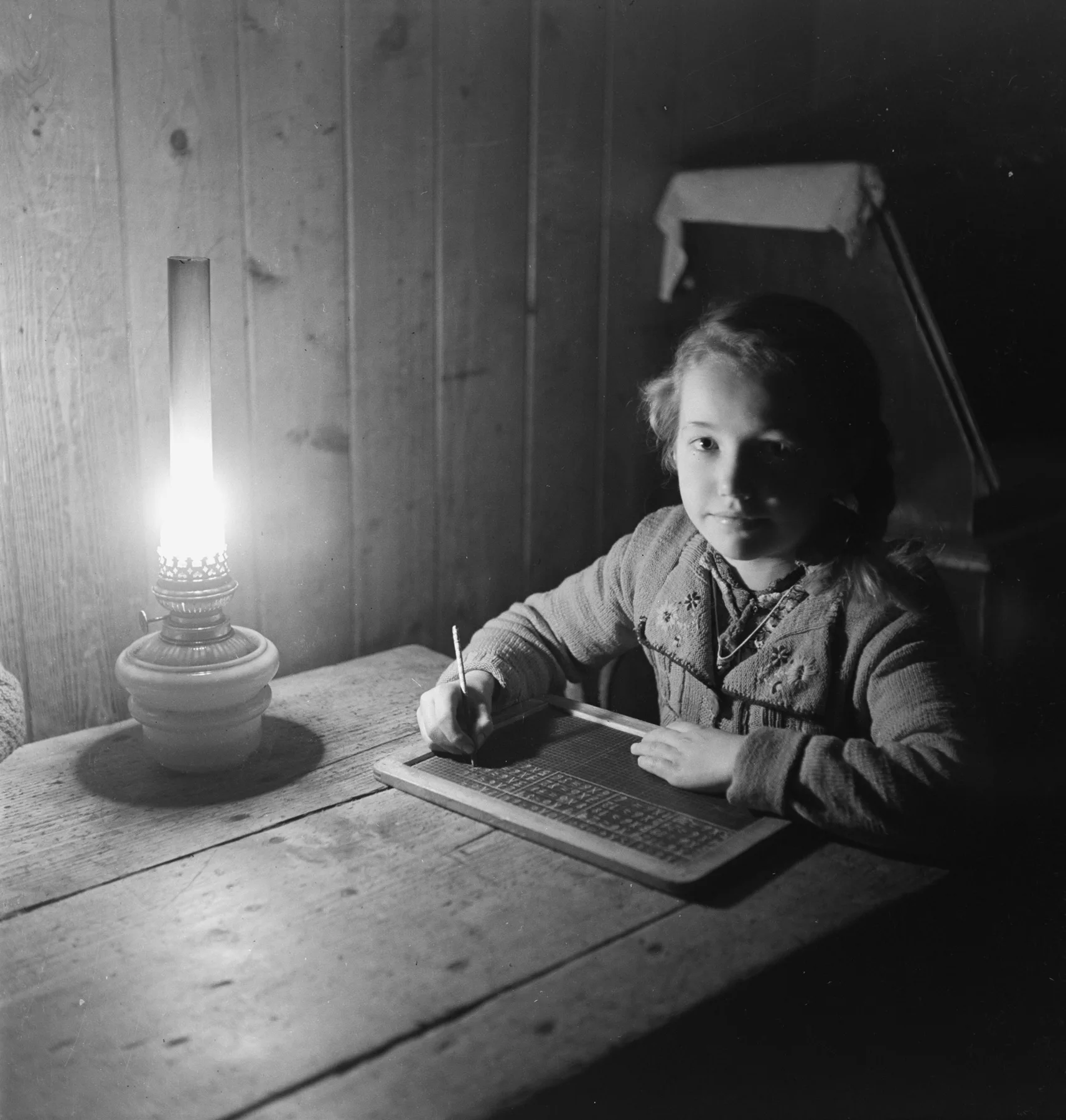 Ein Mädchen schreibt mit Griffel auf eine Schiefertafel, 1930-1950.