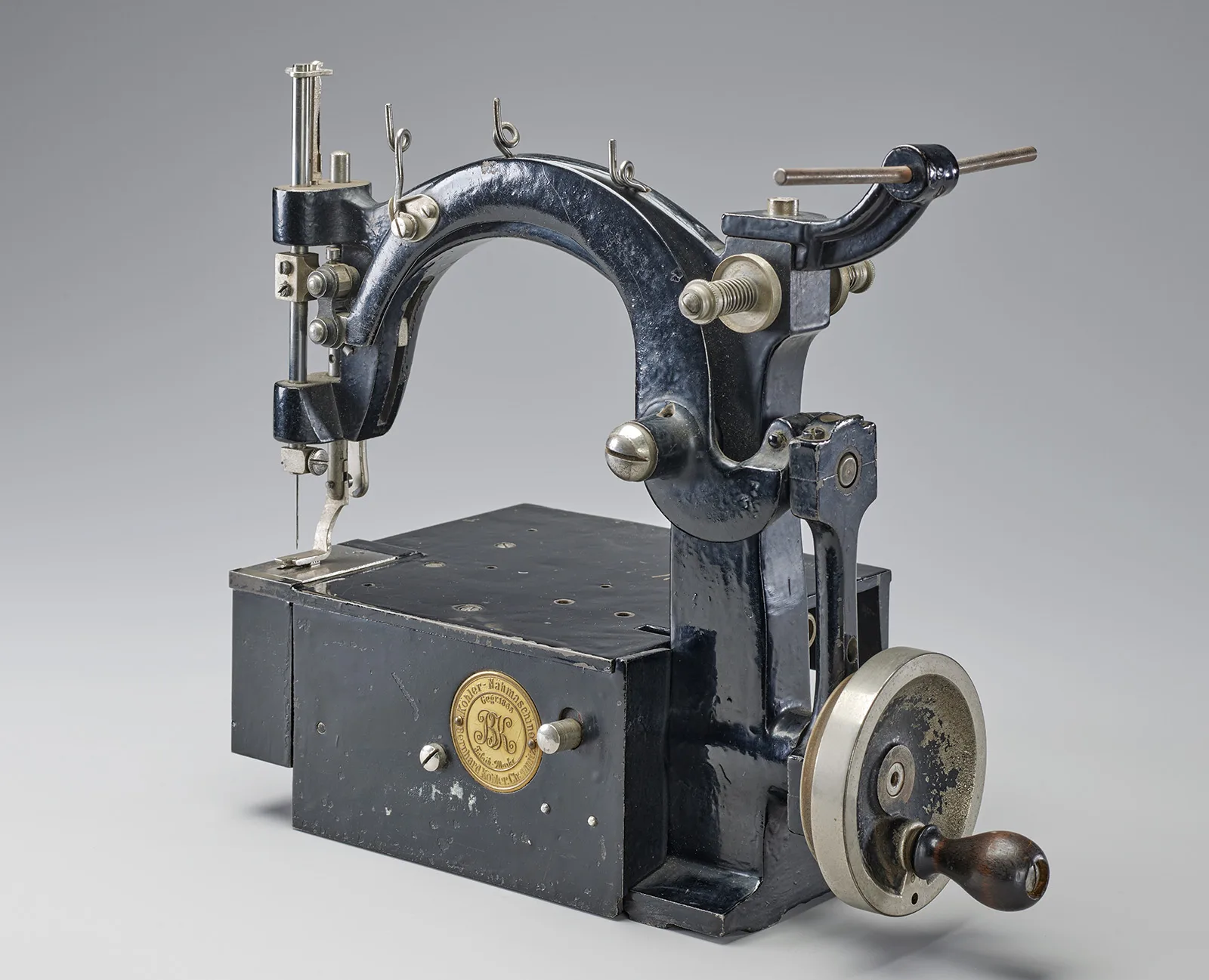 Die Entwicklung der Nähmaschine macht die Handschuhherstellung effizienter. In der gleichen Zeit, in welcher ein Handschuh von Hand zusammengenäht wird, können mit der motorbetriebenen Nähmaschine mehrere Paare fertiggestellt werden. Nähmaschine mit Motorantrieb und Handkurbel aus der Handschuhmacherei Wiessner.