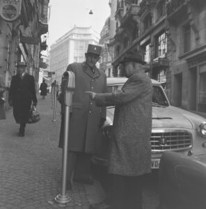 A traffic policeman and a pedestrian next to a parking meter, Lausanne, 1959