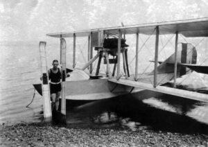 Ralph Samuelson, inventeur du ski nautique, pose devant un hydravion avec lequel il s'est fait tracter sur l'eau, 1925.