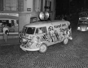 A VW bus with loudspeakers and the message “Kampf dem Schund” leads the procession through Brugg.