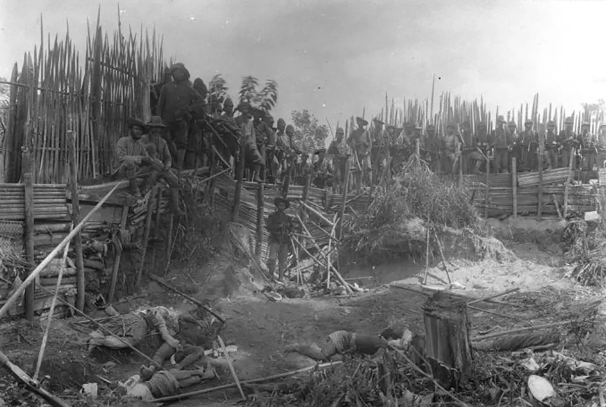 Soldaten der niederländischen Kolonialarmee posieren vor getöteten Dorfbewohnerinnen und Dorfbewohnern in Kuta Reh, Sumatra.