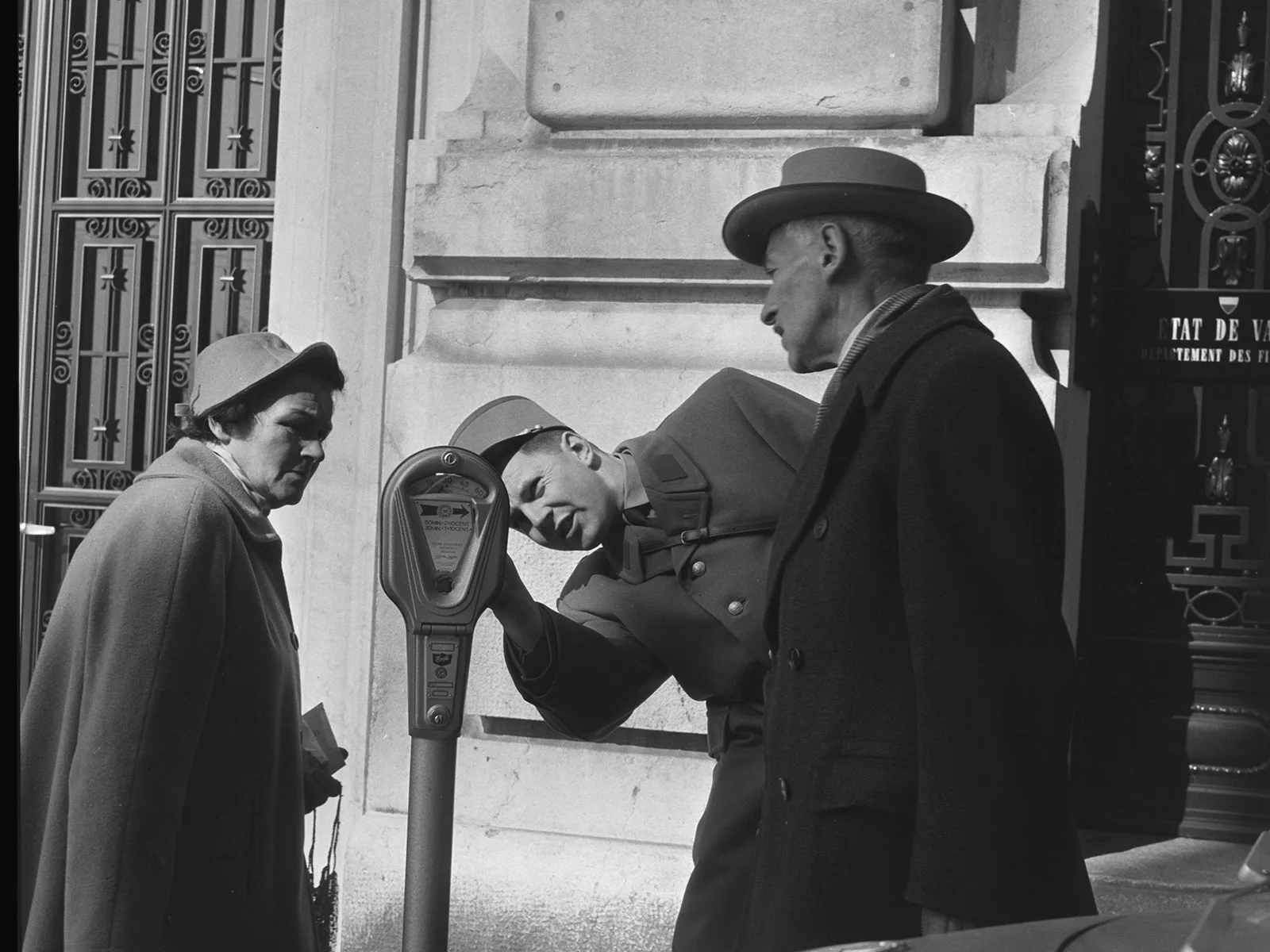 Ein Polizist demonstriert Passanten eine Parkuhr in Lausanne, 1959