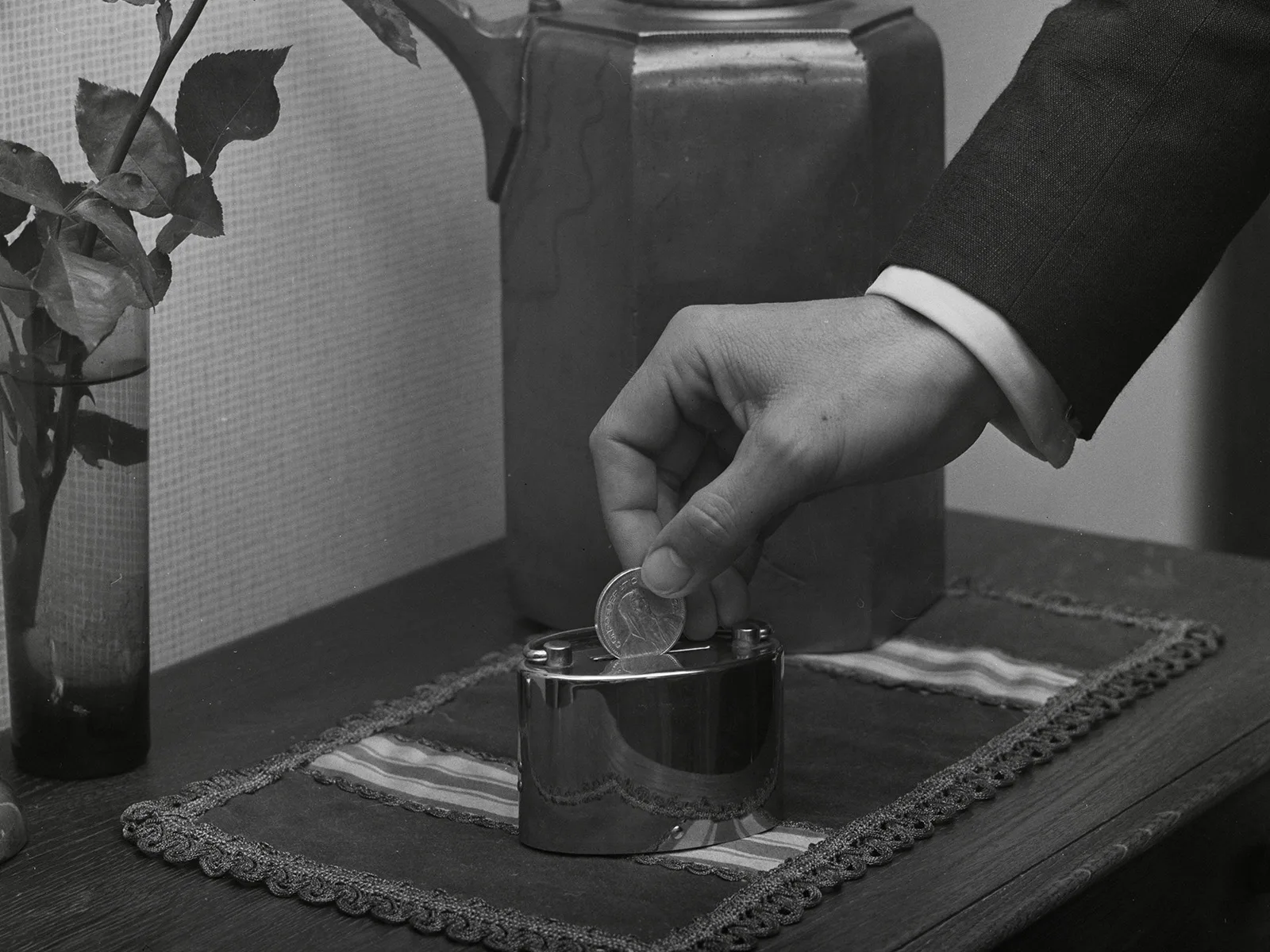 A daily reminder to save at home: a man places a five-franc coin into a money box, 1963. Comet Photo AG.