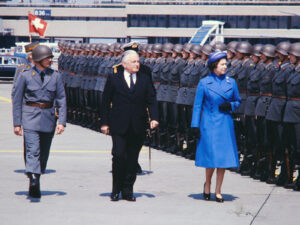 Visite officielle de la reine Élizabeth II en Suisse en 1980. La souveraine passe en revue la garde d’honneur à l’aéroport de Zurich-Kloten en compagnie du président de la Confédération Georges-André Chevallaz.
